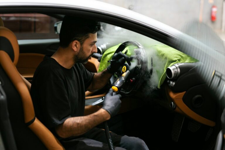Man steam-cleans the interior of a car.